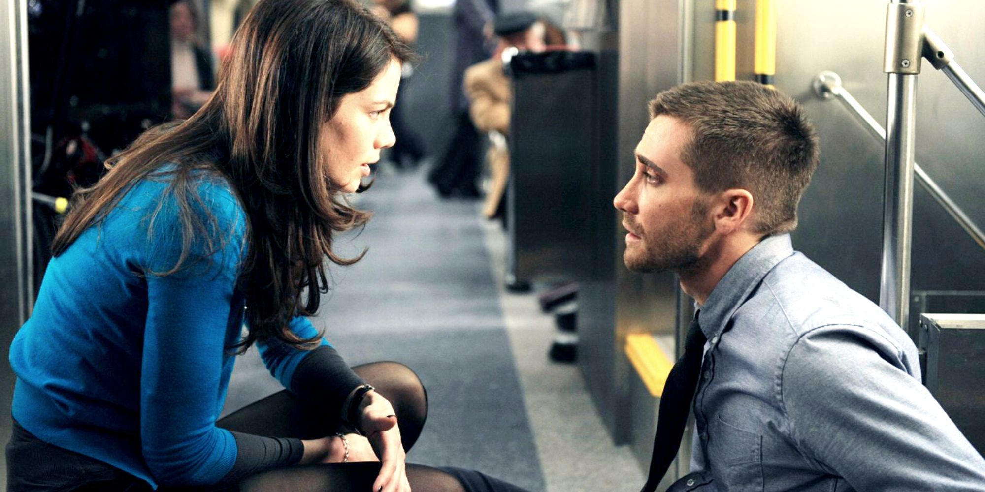 Michelle Monaghan crouching down in front of Jake Gyllenhaal sitting down on a train inSource Code