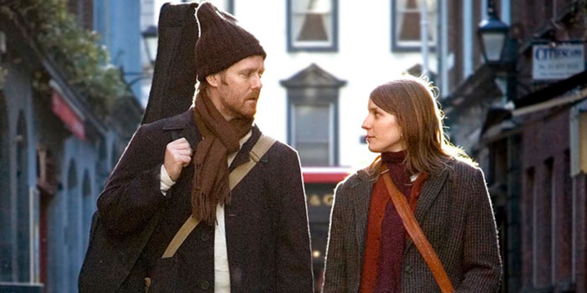 A man and a woman looking at each other while walking down the street in Once (2007) (1)