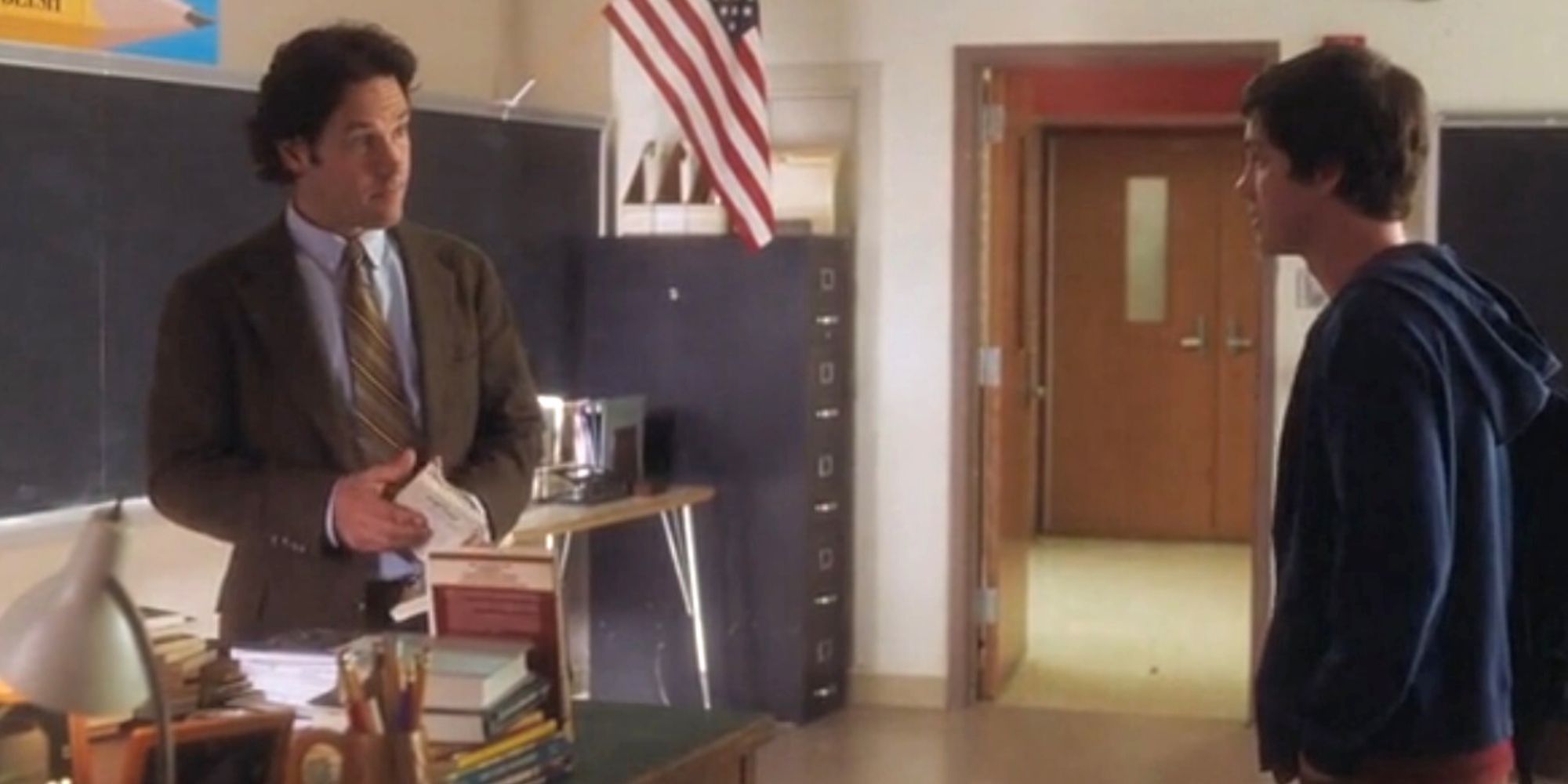 Paul Rudd debout à un bureau en face de Logan Lerman dans une salle de classe dans The Perks of Being a Wallflower.