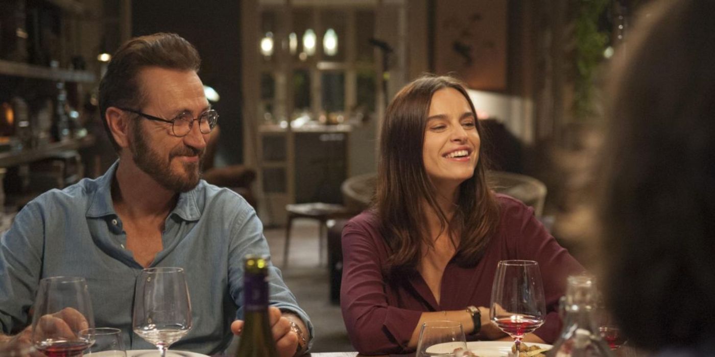 Rocco, interpretado por Marco Giallini, e Eva, interpretada por Kasia Smutniak, riem na mesa de jantar em 'Perfect Strangers'.