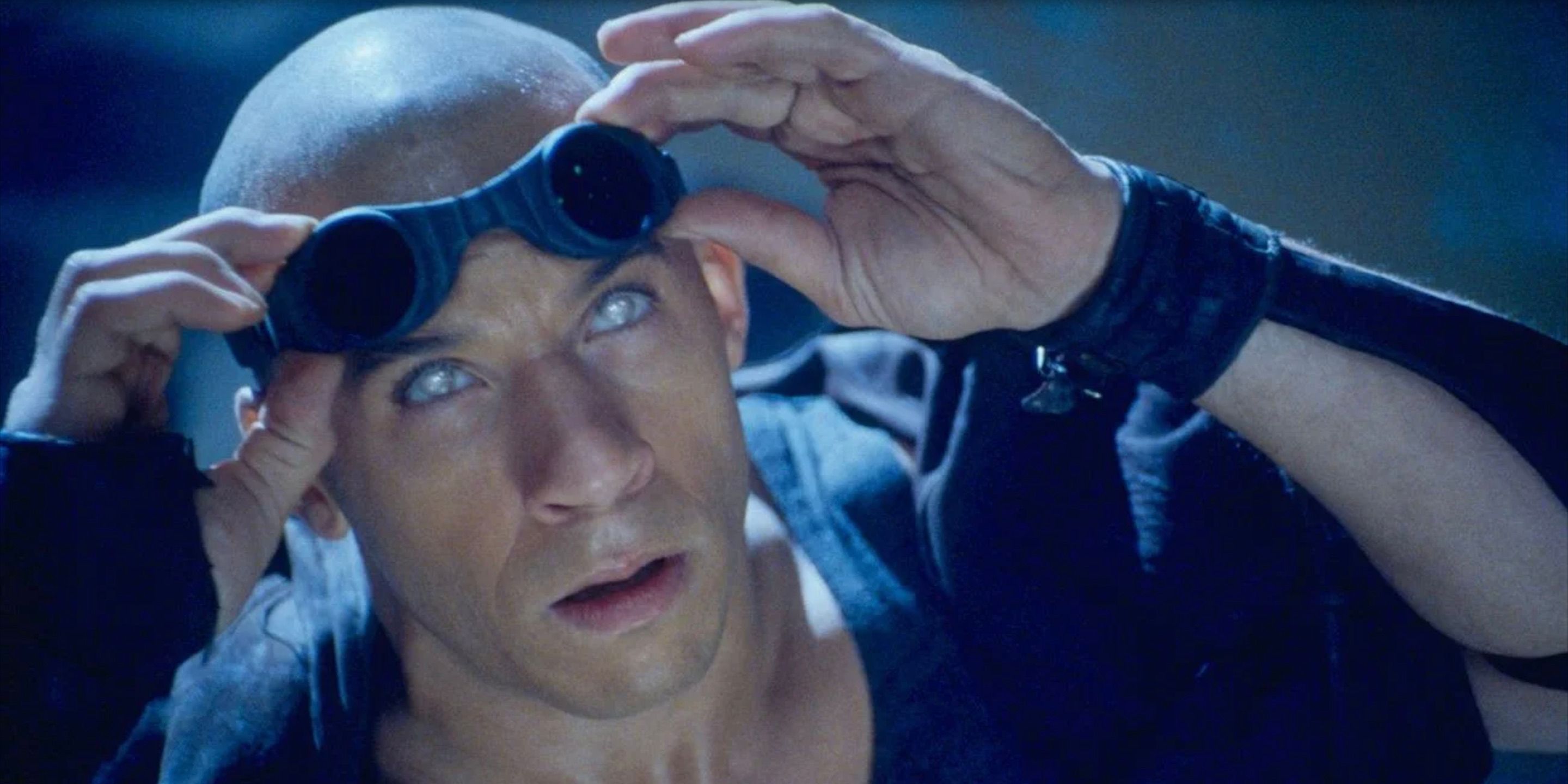 Vin Diesel as Riddick takes his goggles off to look up at the sky in Pitch Black