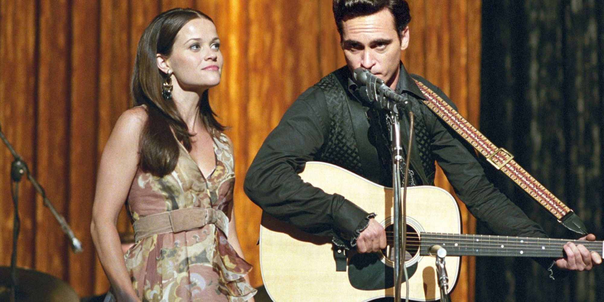 Reese Witherspoon standing next to Joaquin Phoenix on stage singing together in Walk the Line