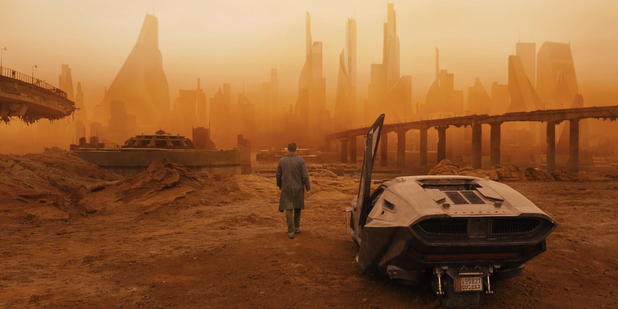 A man walking away from a car and into a dilapidated city in Blade Runner 2049
