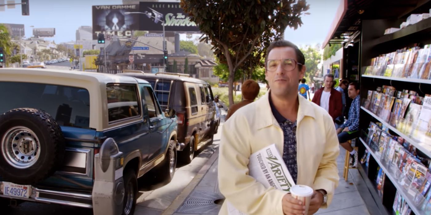 Sandy Wexler, played by Adam Sandler, happily walking down the street holding a cup of coffee and a copy of Variety in Netflix's 'Sandy Wexler.'