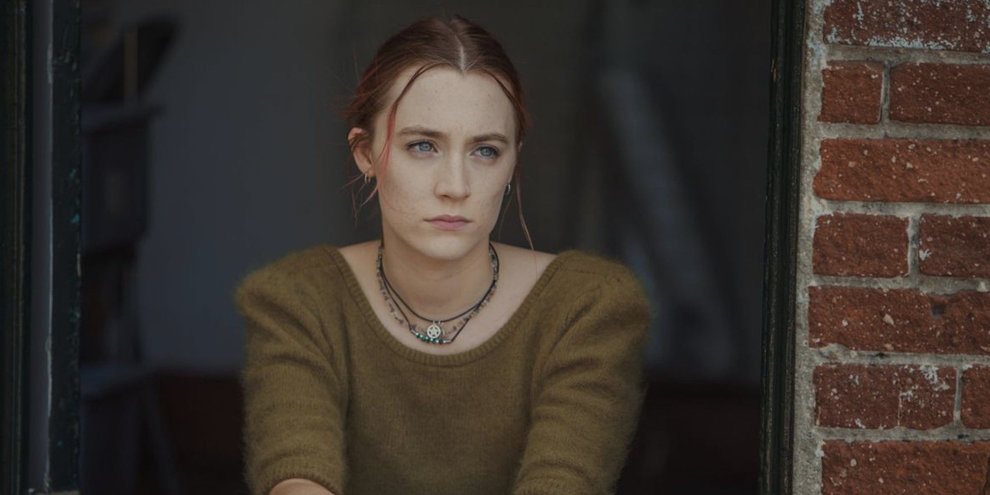 Saoirse Ronan sitting and looking to the distance while frowning in 'Lady Bird'