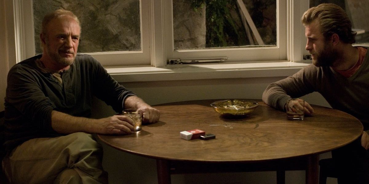Le père et le fils sont assis à une table et boivent du whisky.