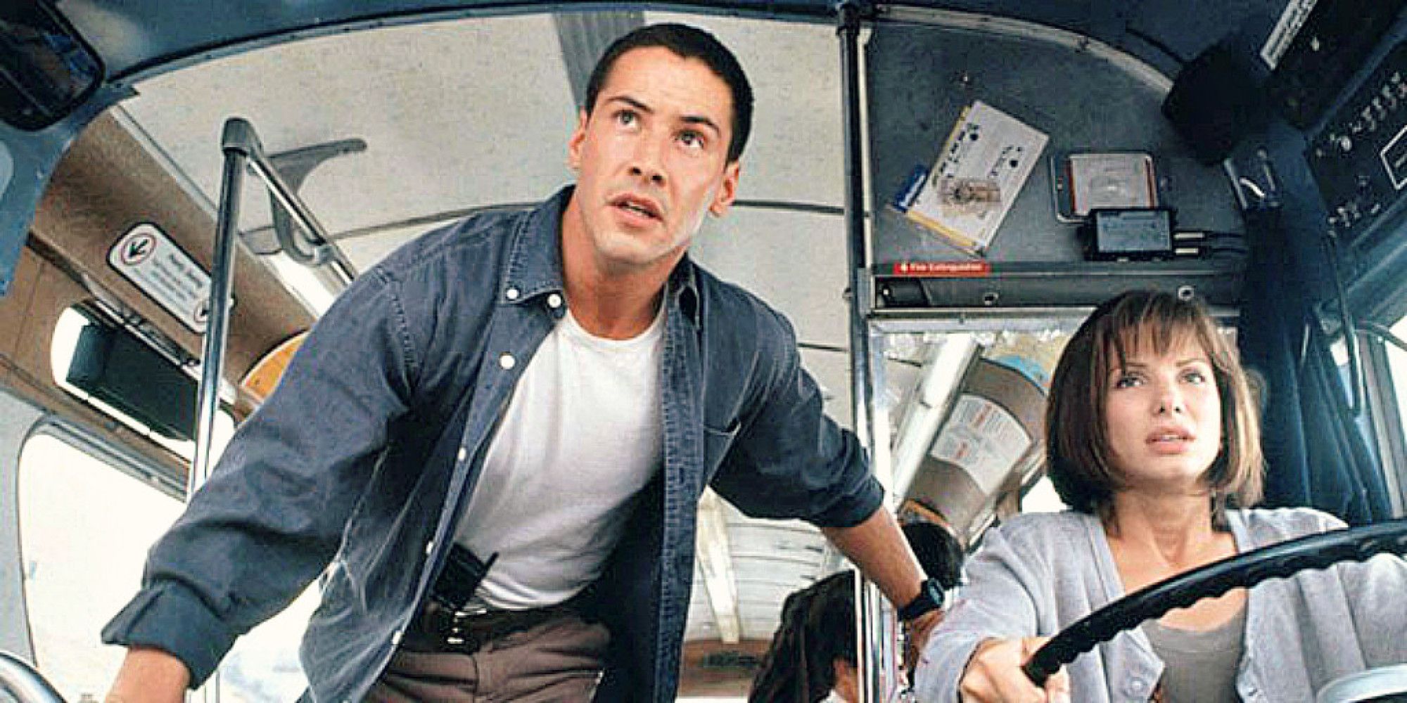 Sandra Bullock driving a bus as Keanu Reeves watches on in Speed