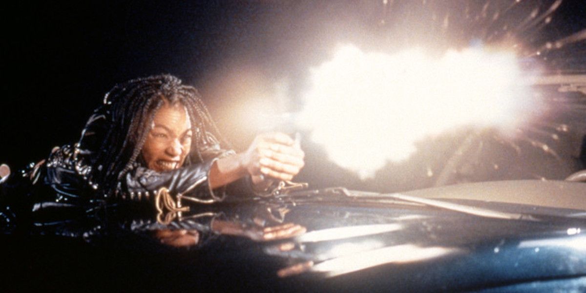 Angela Bassett dans le rôle de Mace tirant avec un pistolet dans Strange Days (1995)