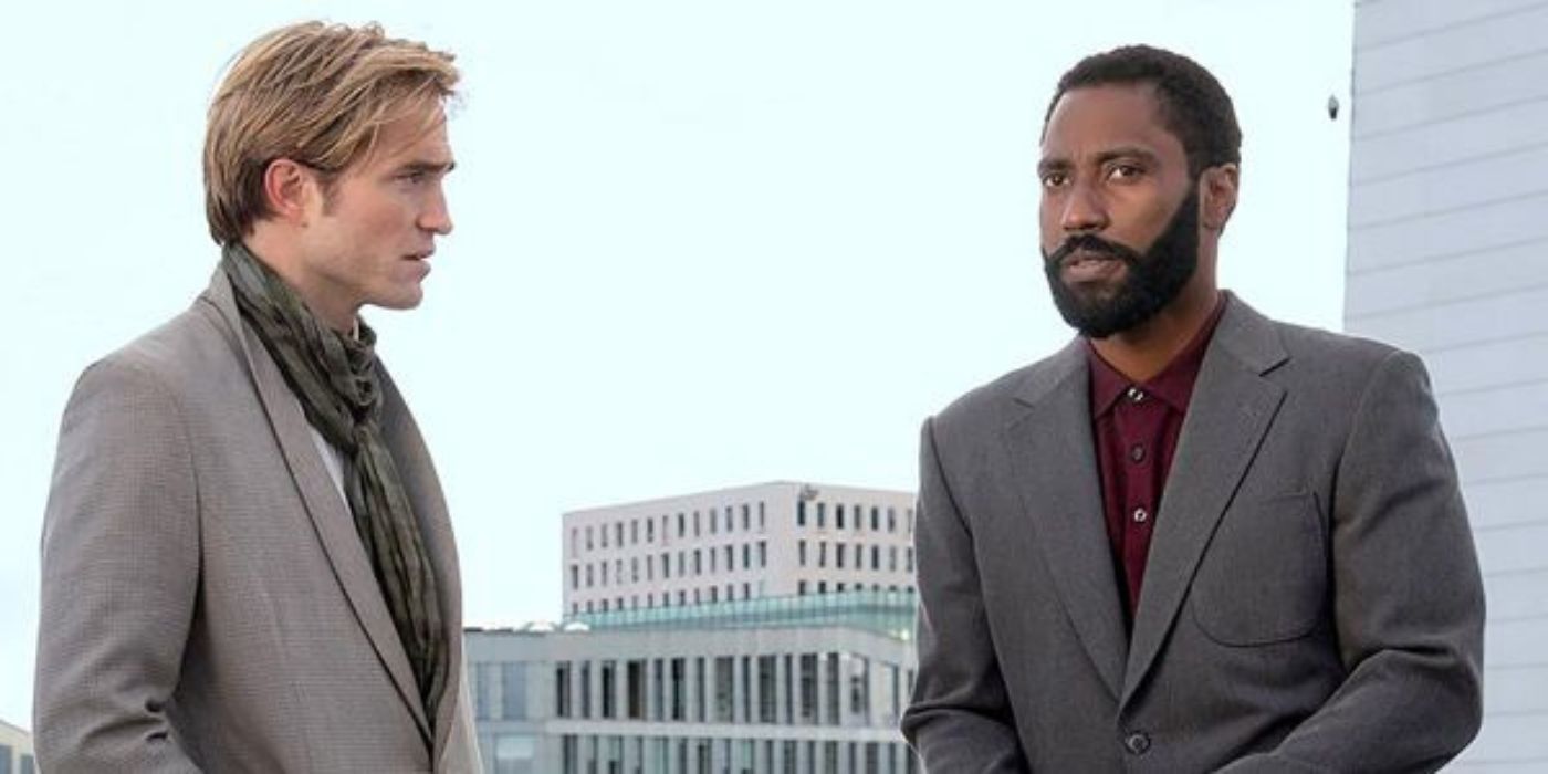 The Protagonist, played by John David Washington, standing next to Neil, played by Robert Pattinson, in front of a building with many windows in 'Tenet.'