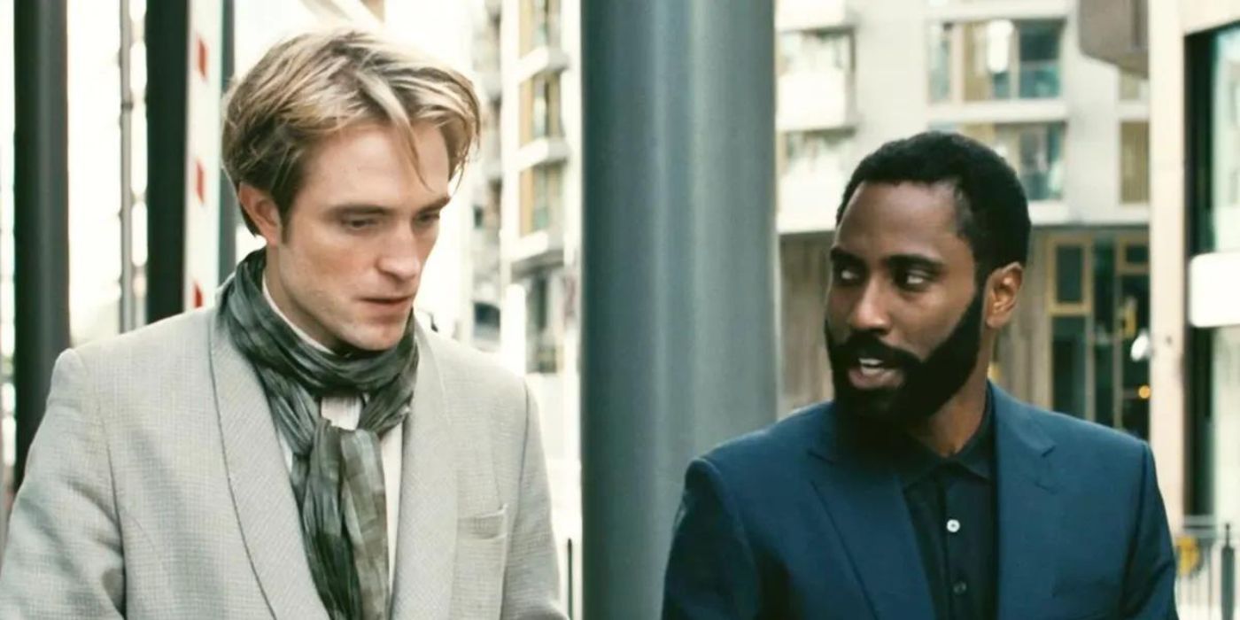 O Protagonista, interpretado por John David Washington, fala com Neil, interpretado por Robert Pattinson, enquanto caminham lado a lado na rua em 'Tenet'.