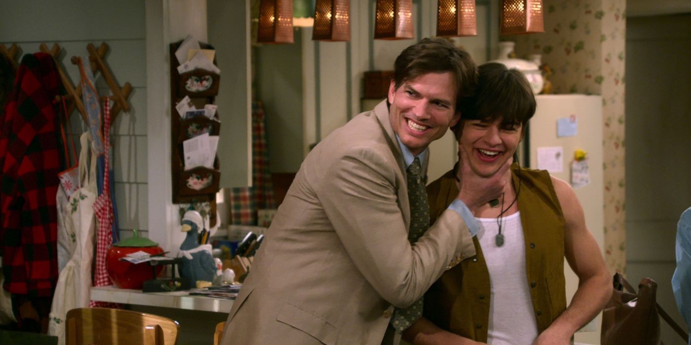 Jay Kelso, played by Mace Coronel, smiling as his dad Michael Kelso, played by Ashton Kutcher, smiles and holds his chin in 'That 90s Show'