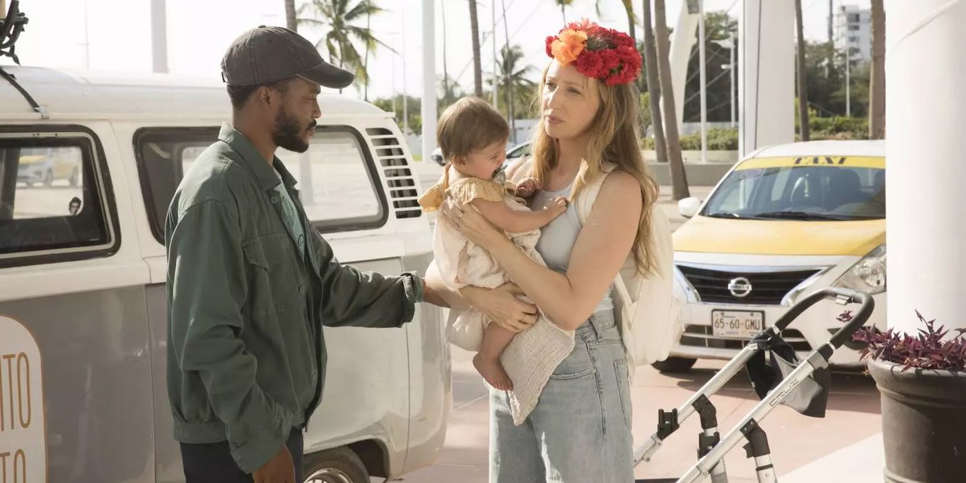 Lex, played by Anna Konkle, holds a baby while her husband Mani, played by Jermaine Fowler, holds his arm out to help her in Hulu's 'The Drop.'