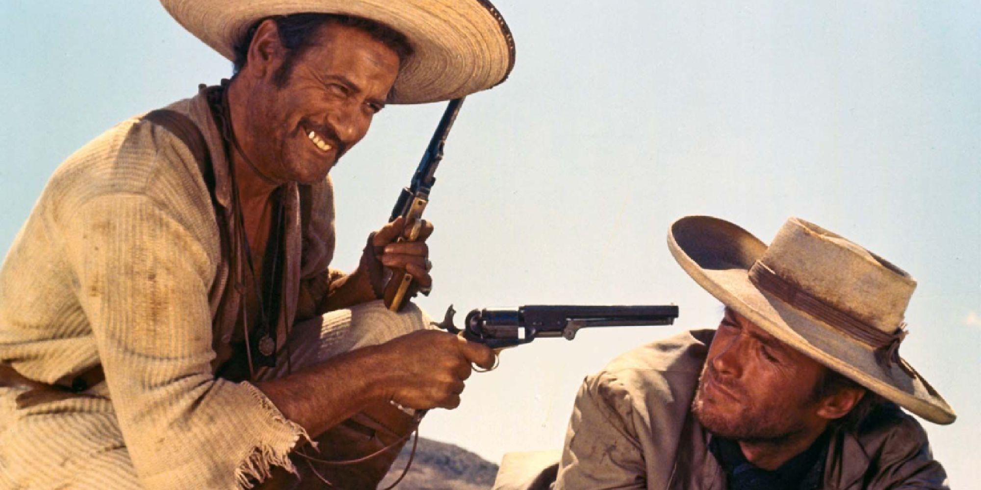 A man smiling holding two guns while another man looks serious in The Good, The Bad, and The Ugly - 1966