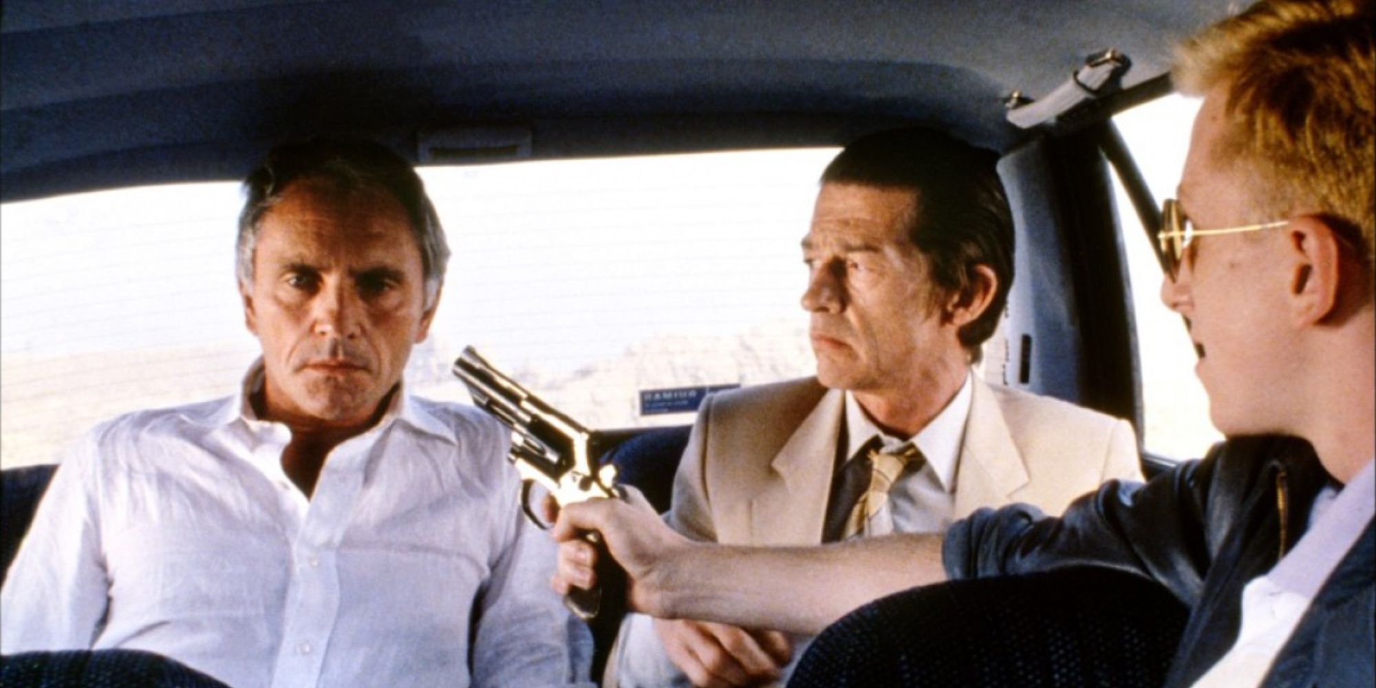 Terence Stamp sitting next to John Hurt with a gun in his face in The Hit