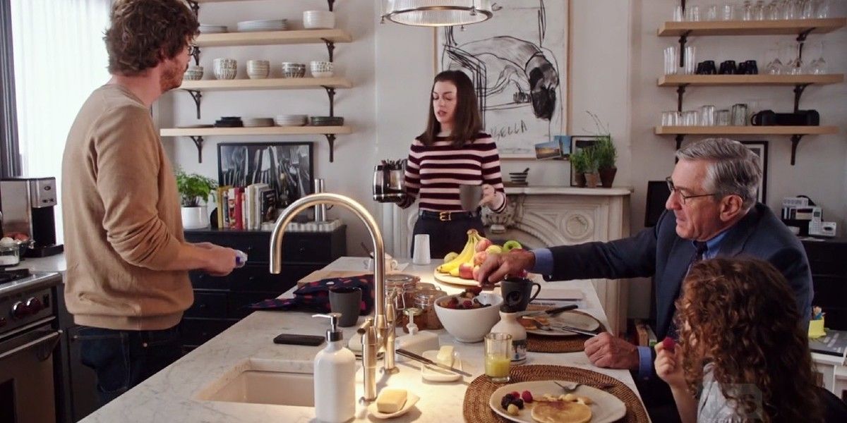 Anne Hathaway como Jules Ostin conversando com sua família na cozinha em The Intern