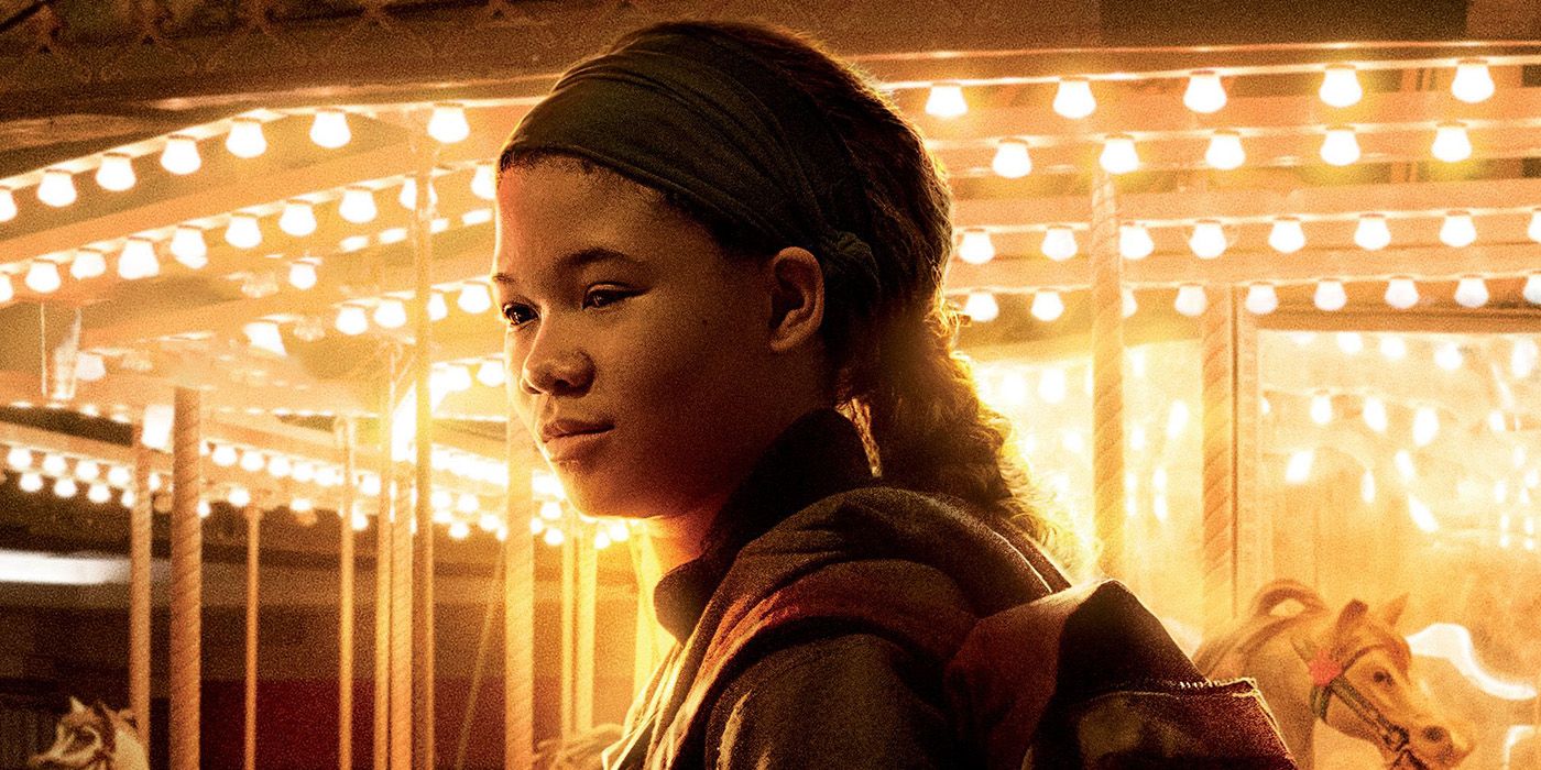 Storm Reid as Riley in The Last of Us standing on front of a merry-go-round.