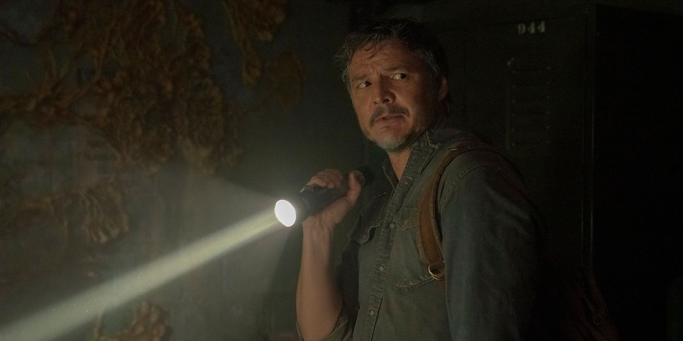 Joel de The Last of Us, l'air effrayé, tenant une lampe de poche allumée.