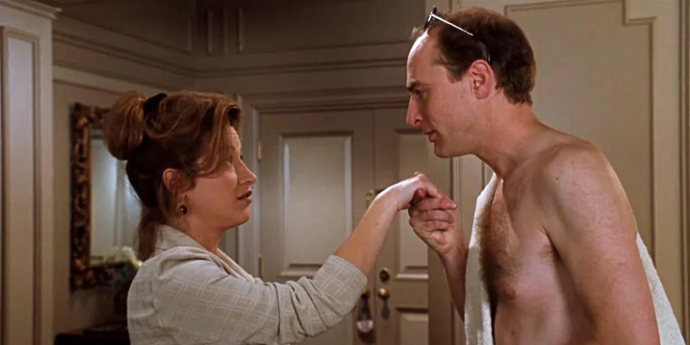 Martin, played by Simon Kunz, with a towel over his shoulder and holding Chessy's, played by Lisa Ann Walter, hand up to his lips in 'The Parent Trap'