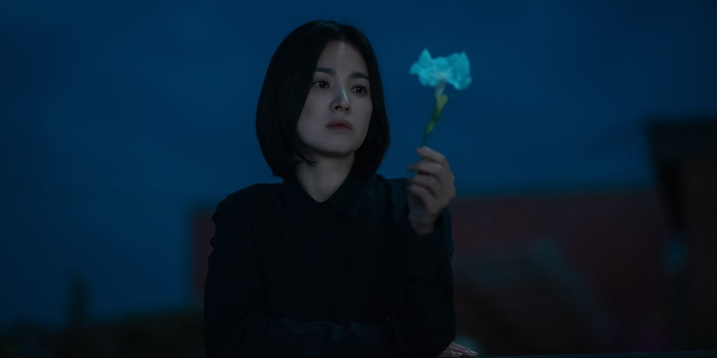 Song Hye-kyo holding a flower in a scene from The Glory. 