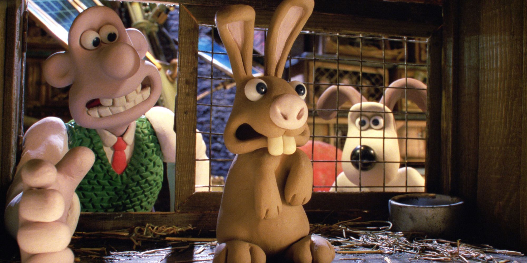 Wallace reaching into a cage to take out a rabbit while Gromit stands behind him in Wallace & Gromit: The Curse of the Were-Rabbit