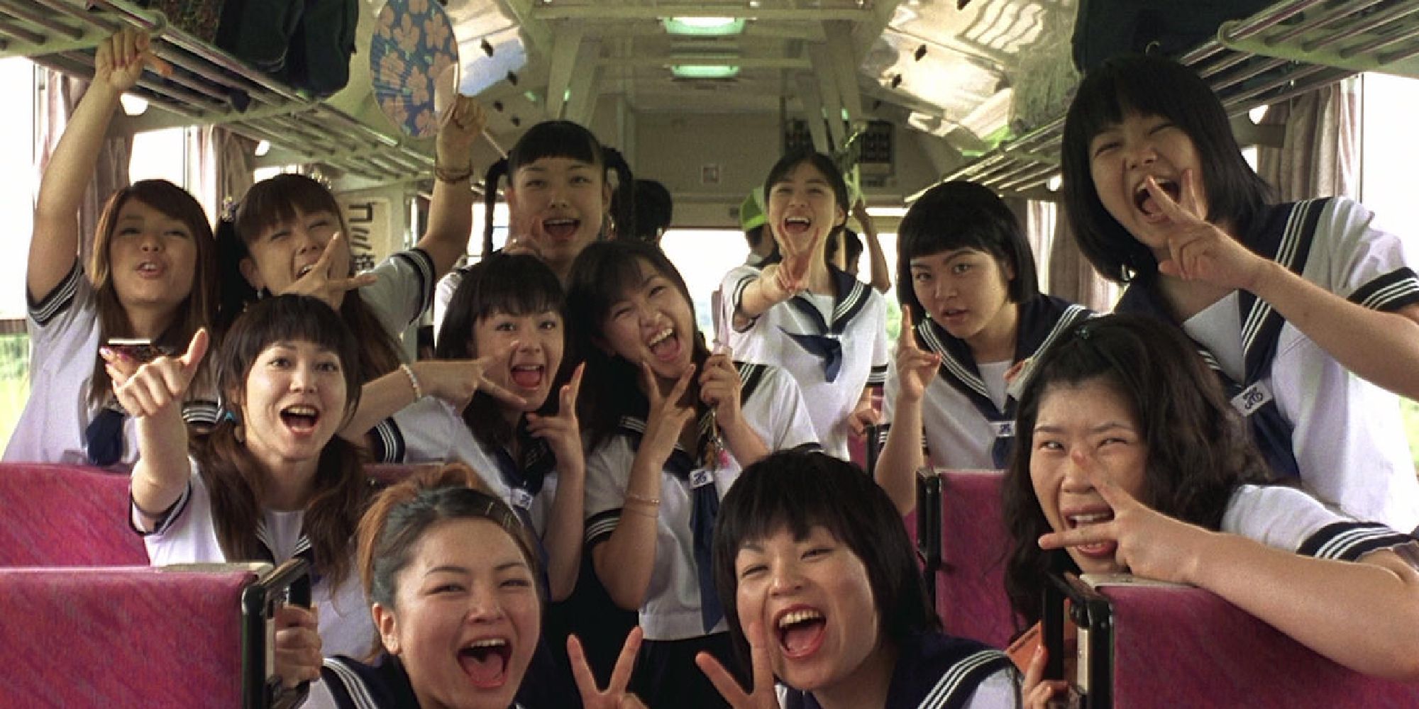 Un groupe d'adolescentes faisant le signe de la paix devant la caméra à l'intérieur d'un bus dans 'Swing Girls'.