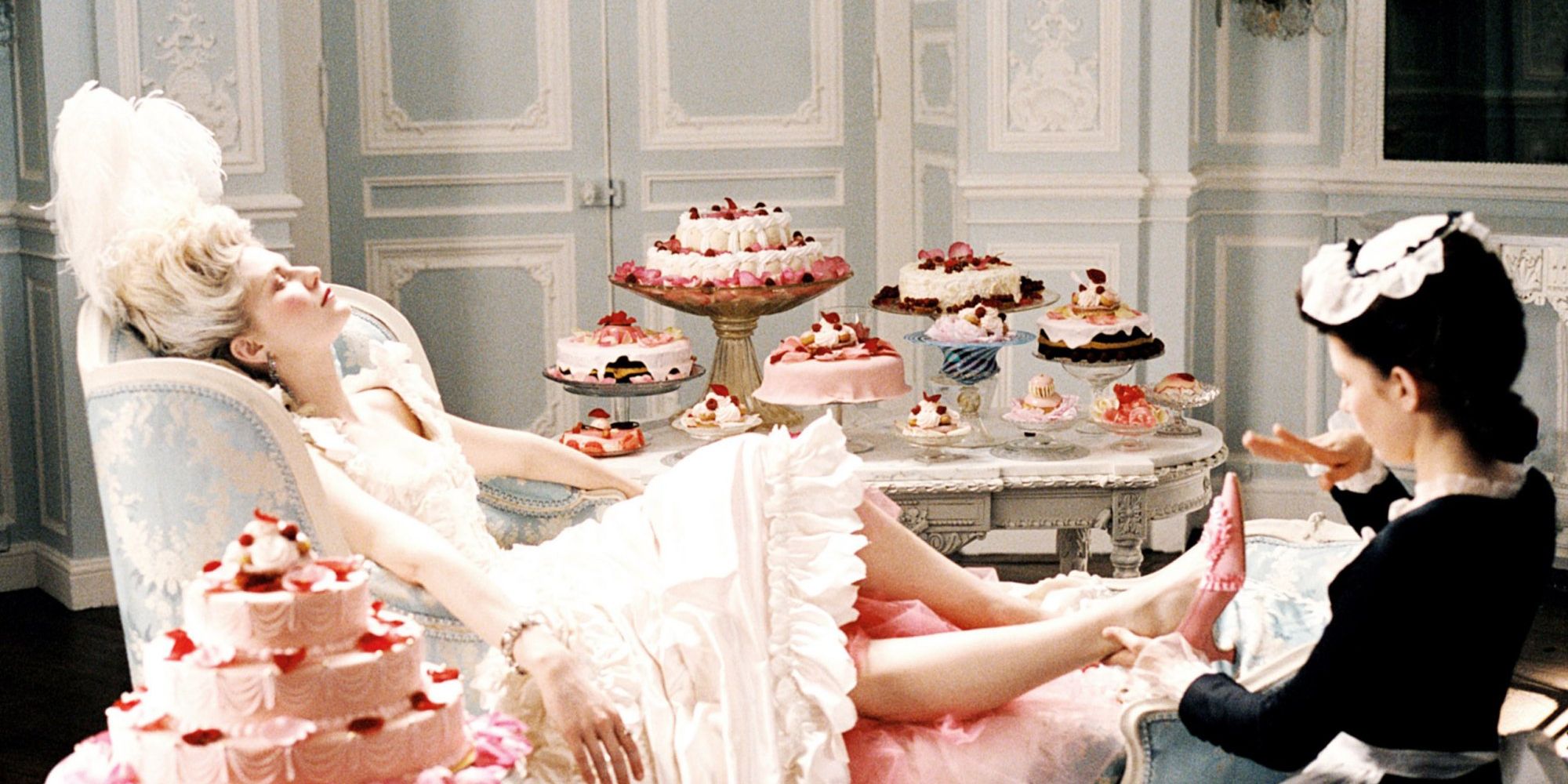 Une photo de Marie-Antoinette où Kirsten Dunst est allongée sur un canapé avec un tas de pâtisseries à côté d'elle
