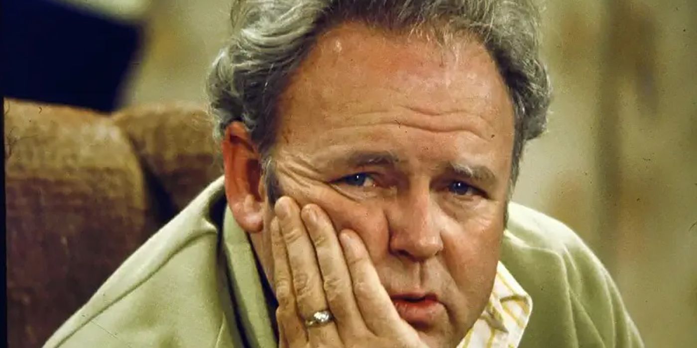 Un gros plan d'Archie Bunker dans 'All in the Family', sa main sur sa joue, l'air exaspéré.