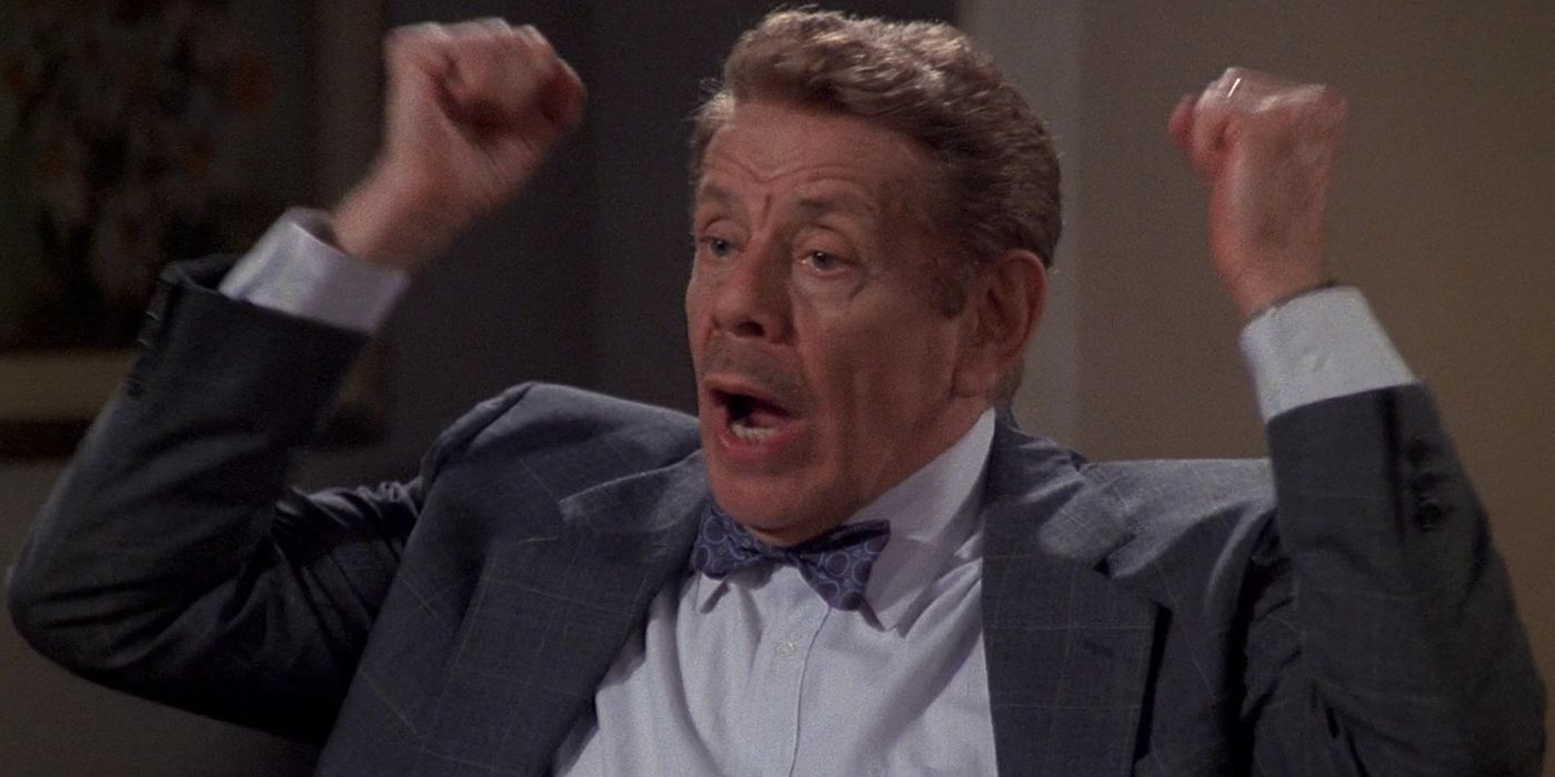 arthur spooner on the king of queens wearing a suit, hands up in the air yelling.