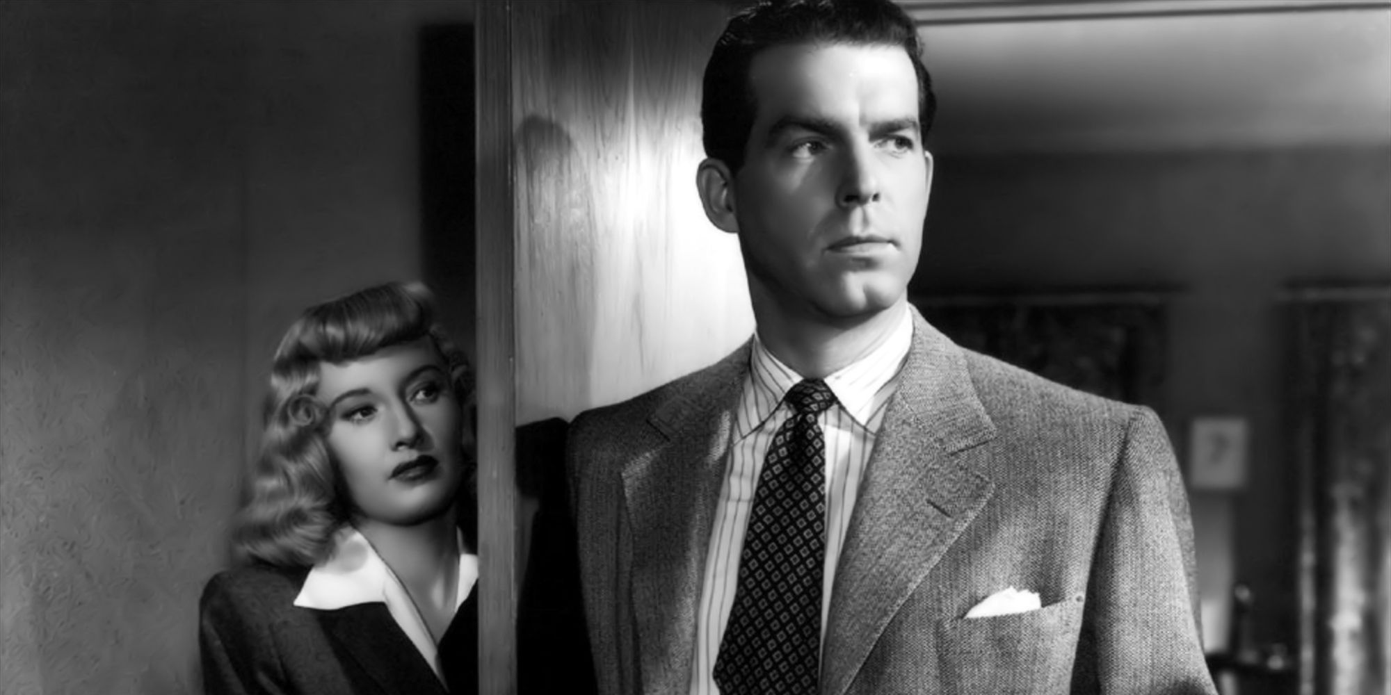 Barbara Stanwyck standing behind a door as Fred MacMurray stands in the door way in Double Indemnity