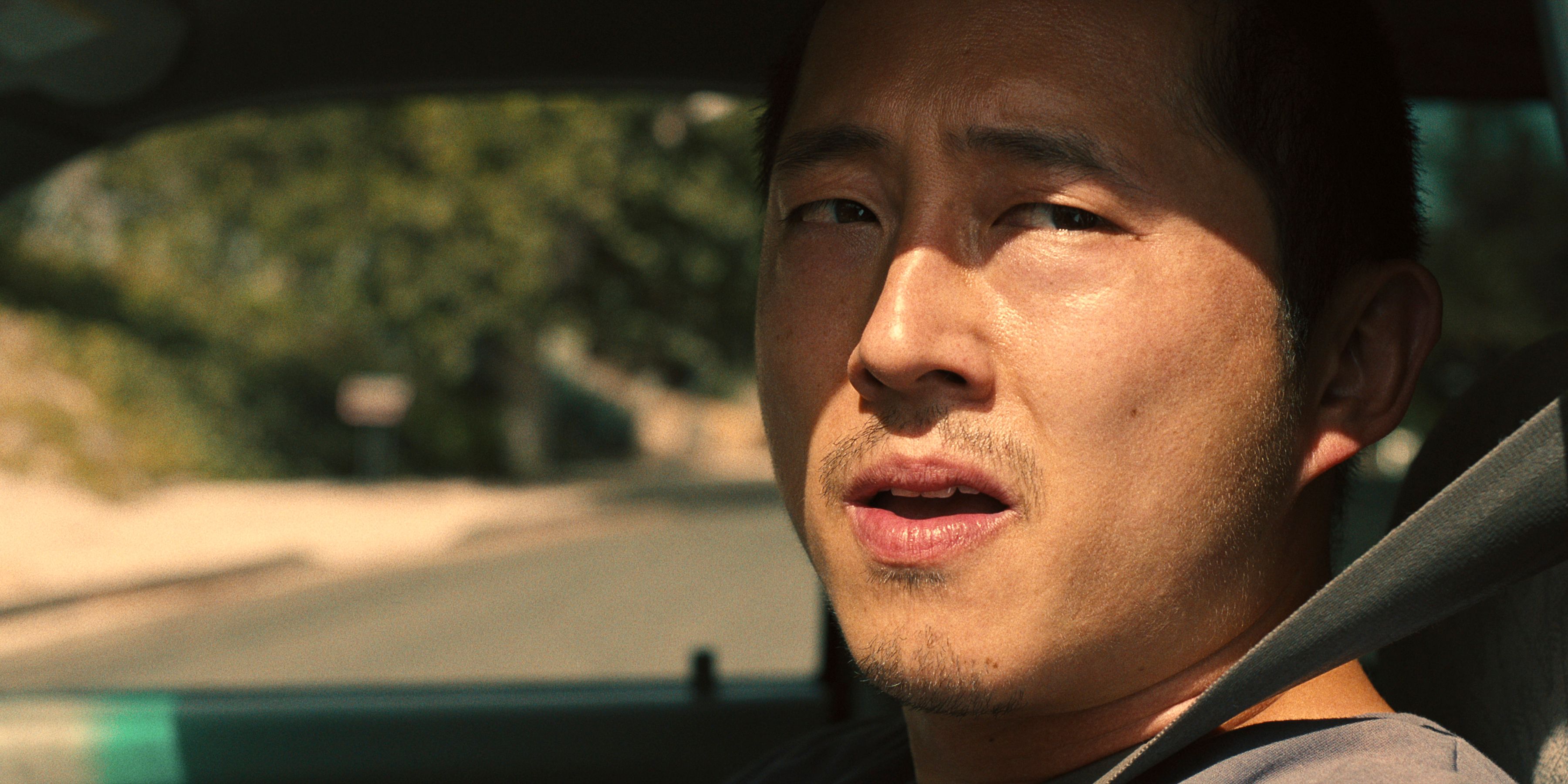 Steven Yeun as Danny Cho looking out of the drivers side window from inside a car in BEEF