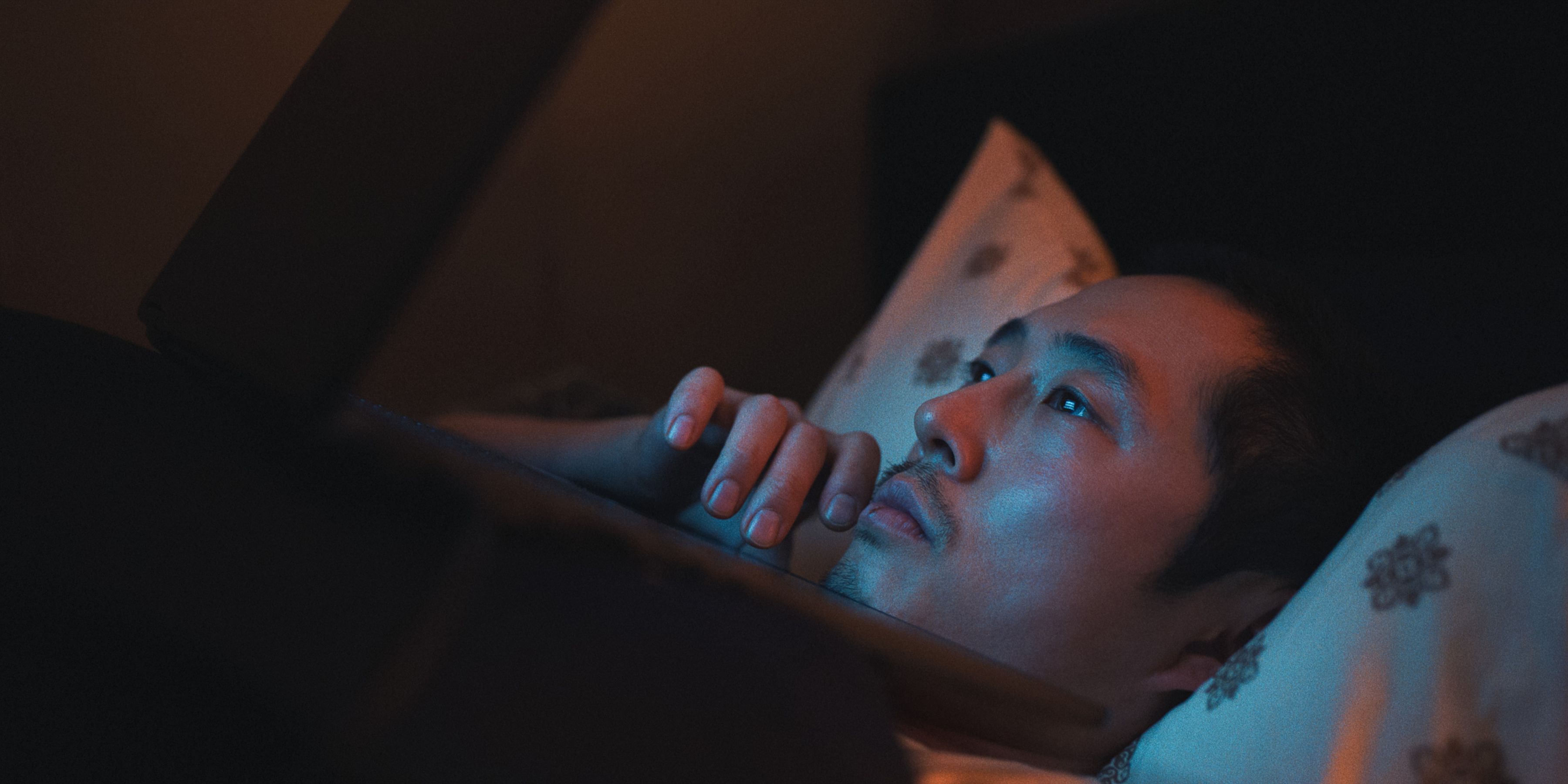 Steven Yeun en tant que Danny Cho au lit sur son téléphone dans BEEF