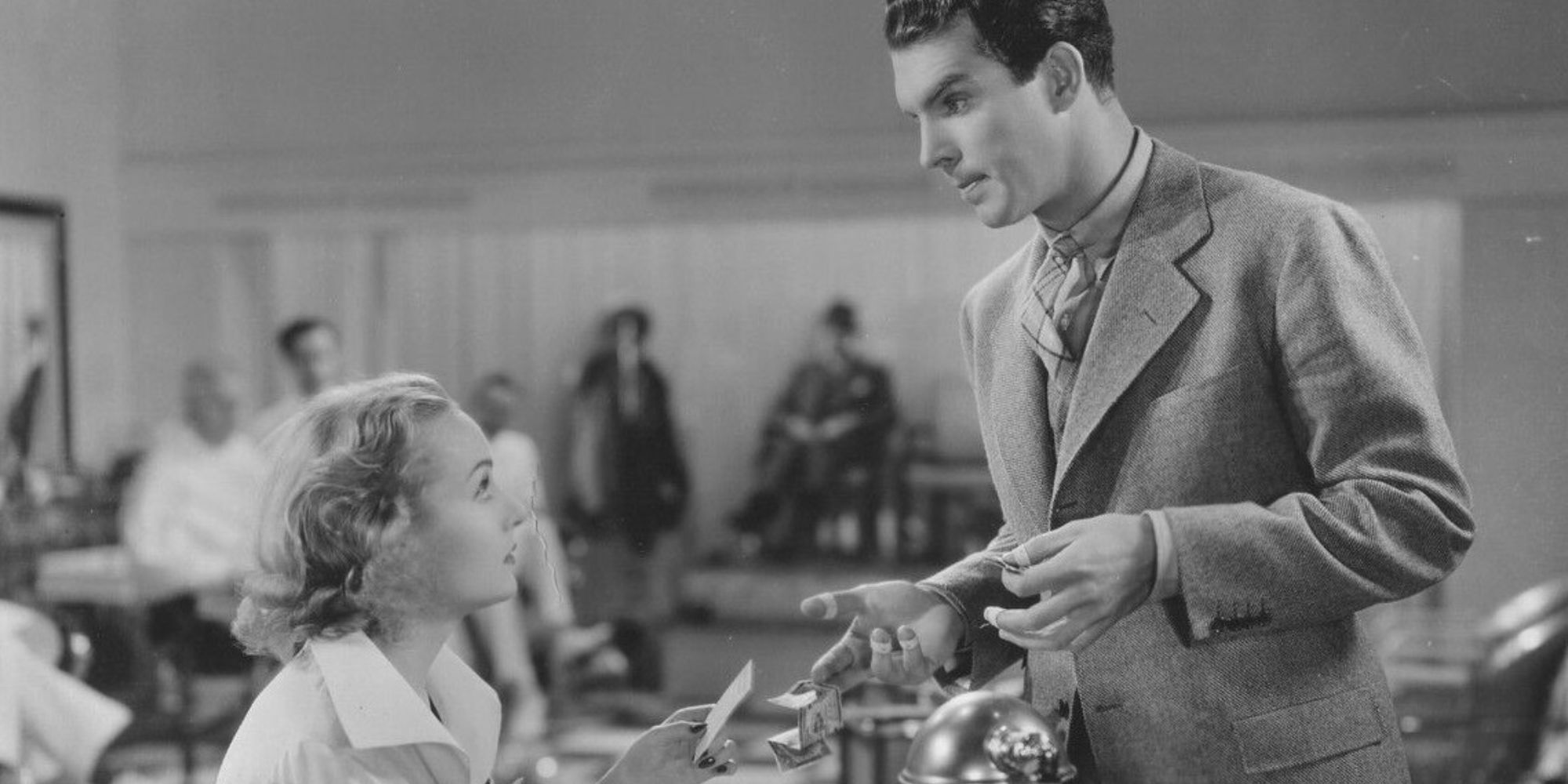 Carole Lombard sitting down looking up at Fred MacMurray standing in front of her in Hands Across the Table