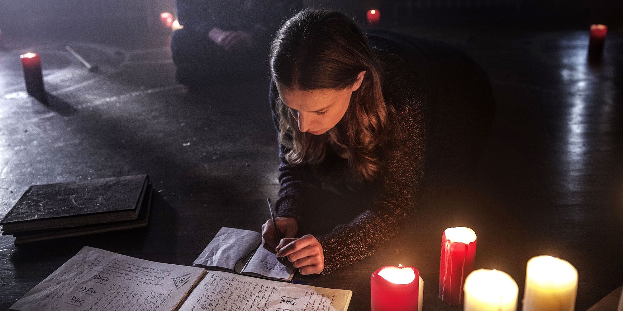 Catherine Walker writing in a notebook surrounded by candles 