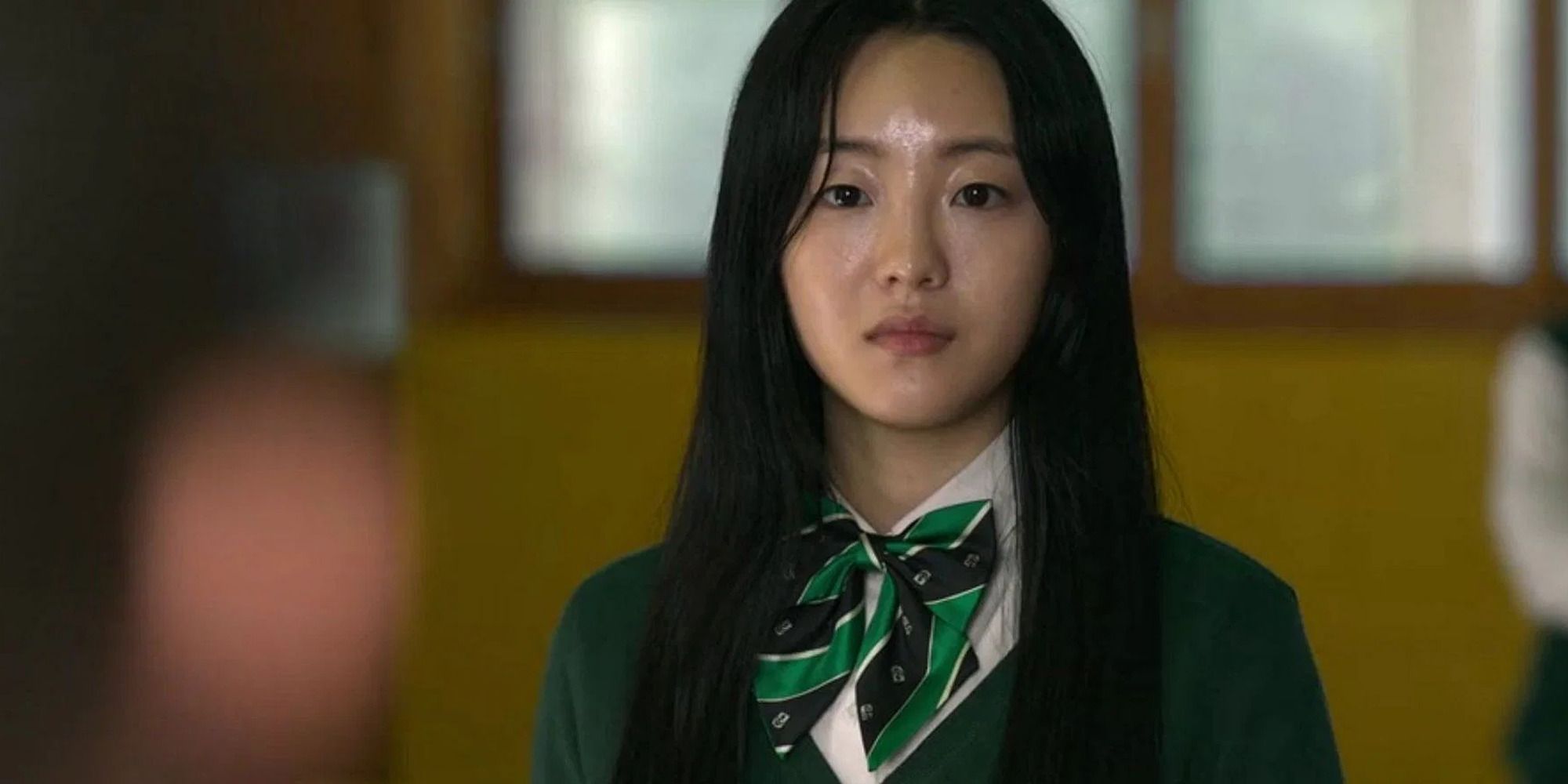 Choi Nam-ra dari All of Us Are Dead dalam setelan hijau melihat ke kamera