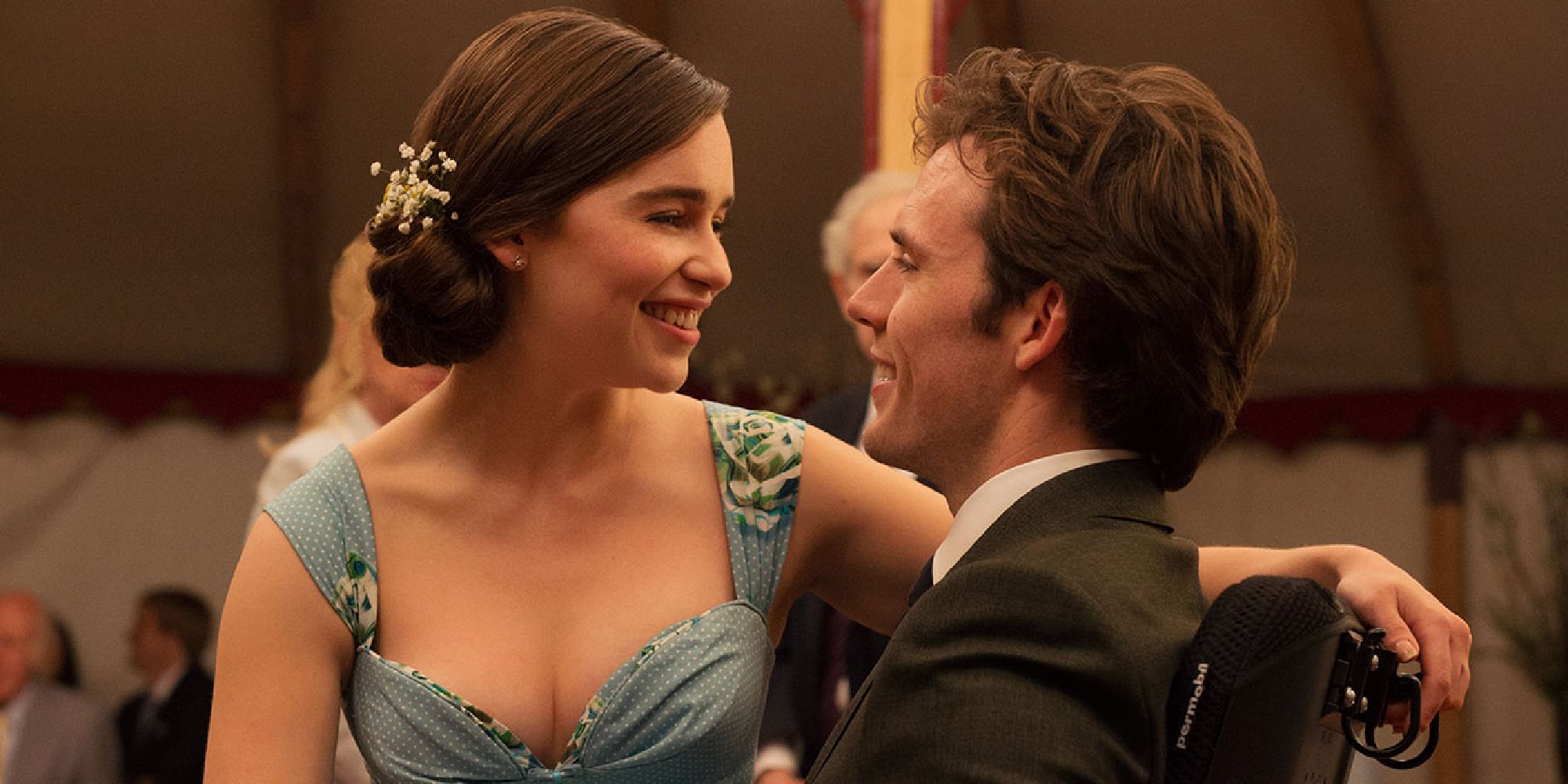 Emilia Clarke sitting in Sam Claflin's lap whilst they both look at each other lovingly in 'Me Before You'