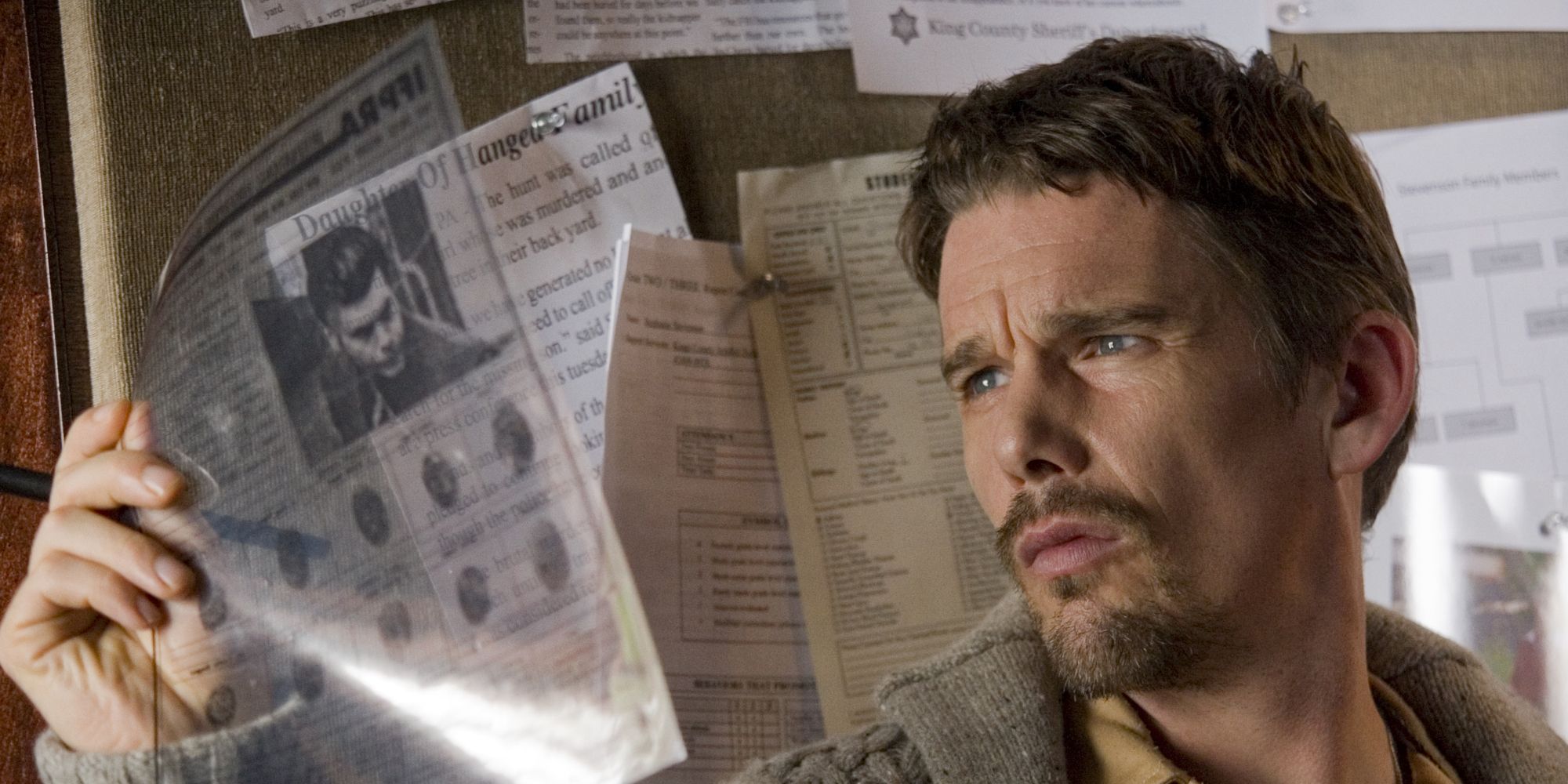 Ethan Hawke looking at a piece of newspaper in 'Sinister'