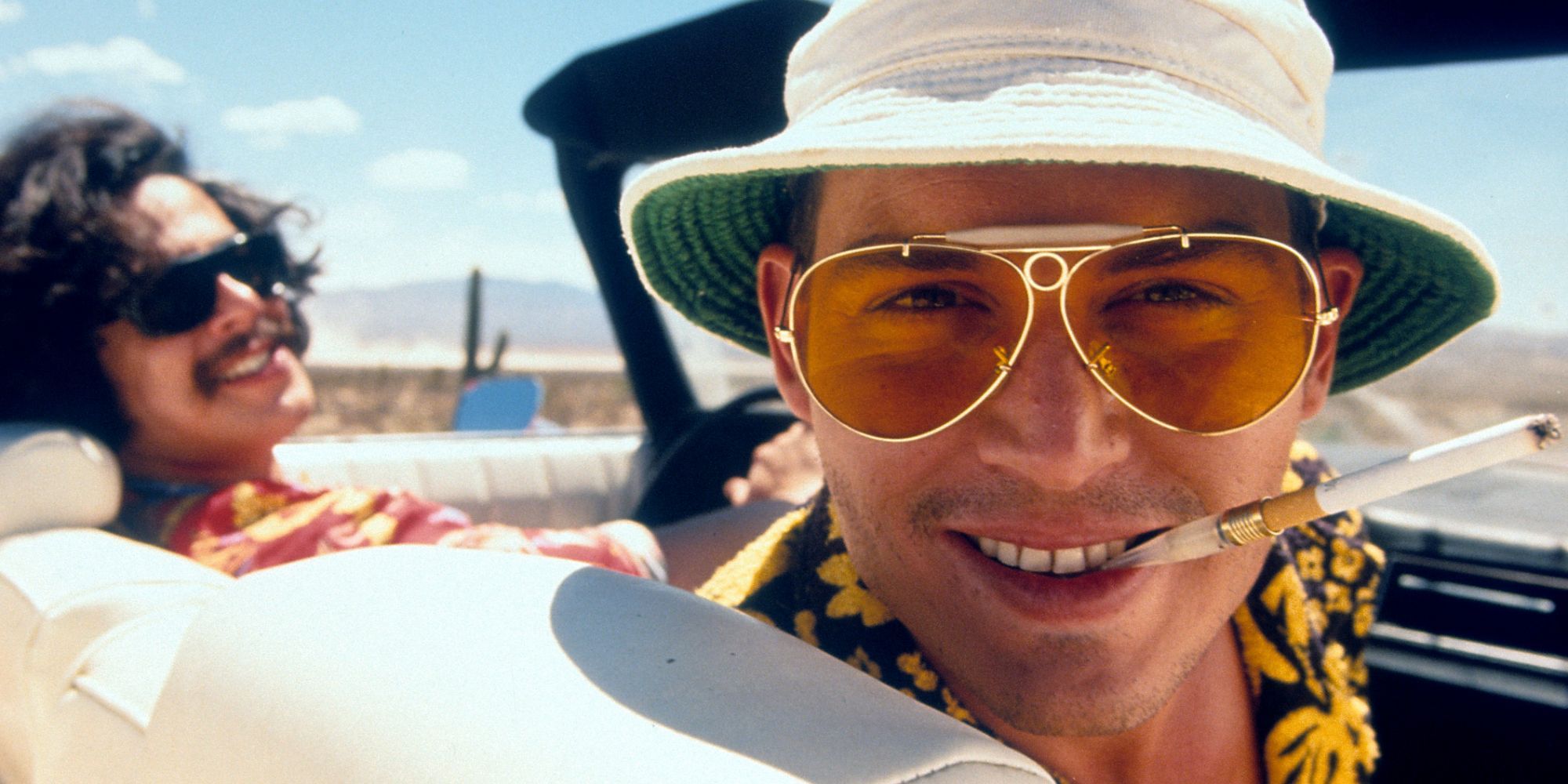 Johnny Depp looking at the camera while Benicio del Toro drives a car in Fear and Loathing in Las Vegas