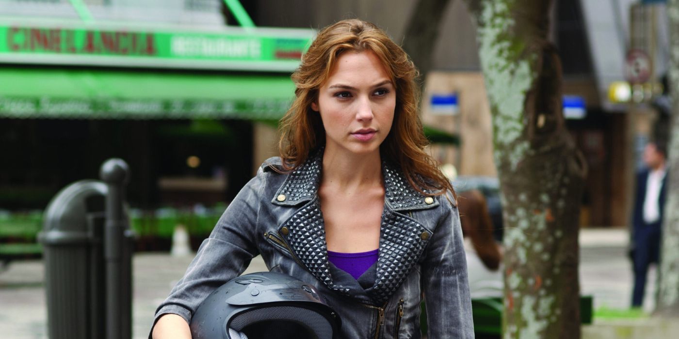 Gal Gadot as Gisele standing on the street holding a motorcycle helmet in Fast & Furious