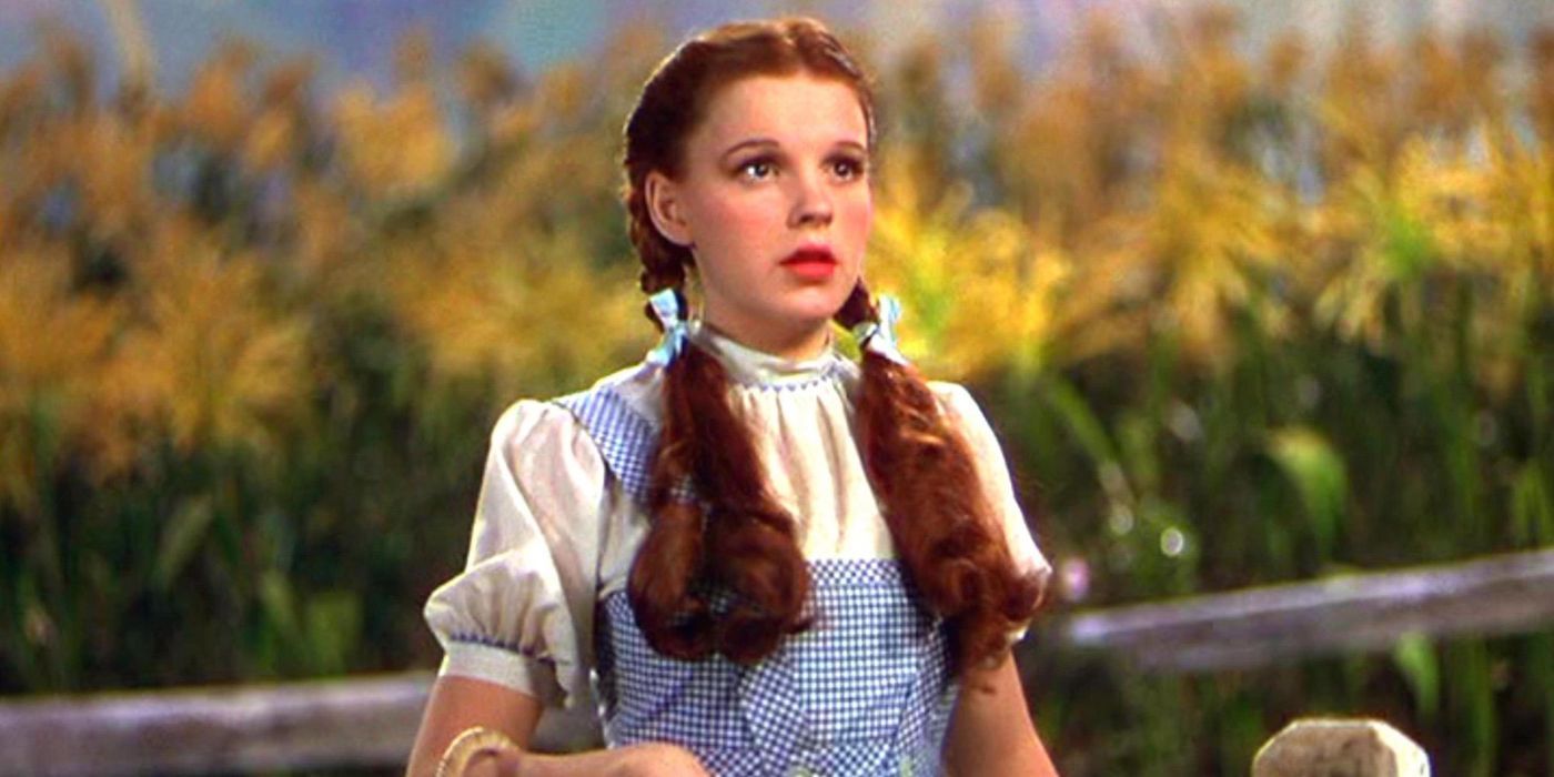 Judy Garland as Dorothy Gale, standing in front of yellow flowers and looking surprised in The Wizard of Oz