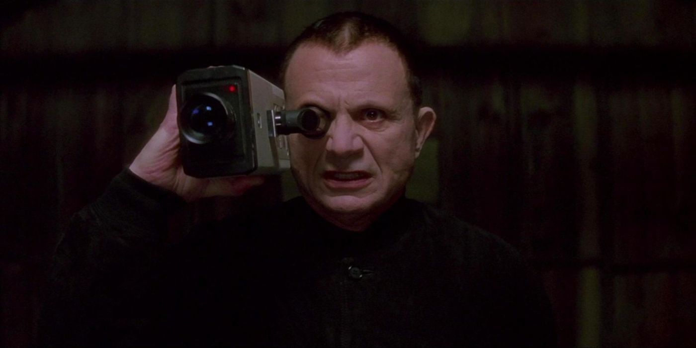 L'homme mystère, joué par Robert Blake, tenant un caméscope devant son œil dans 'Lost Highway'.