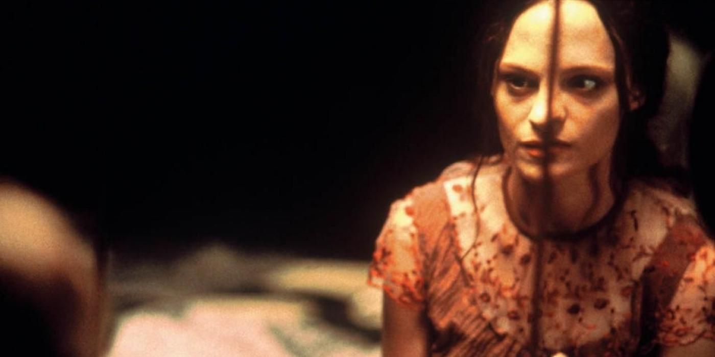 Still from 'May': May (Angela Bettis) looks in a mirror, her face appearing to be split down the center.