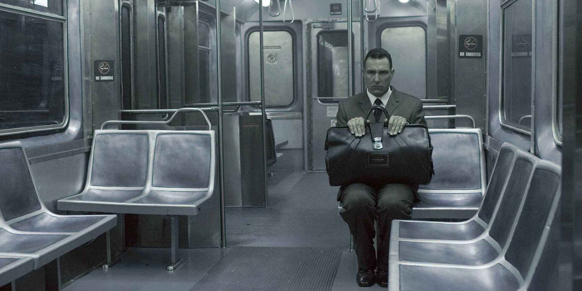 A man sits with his briefcase on a train