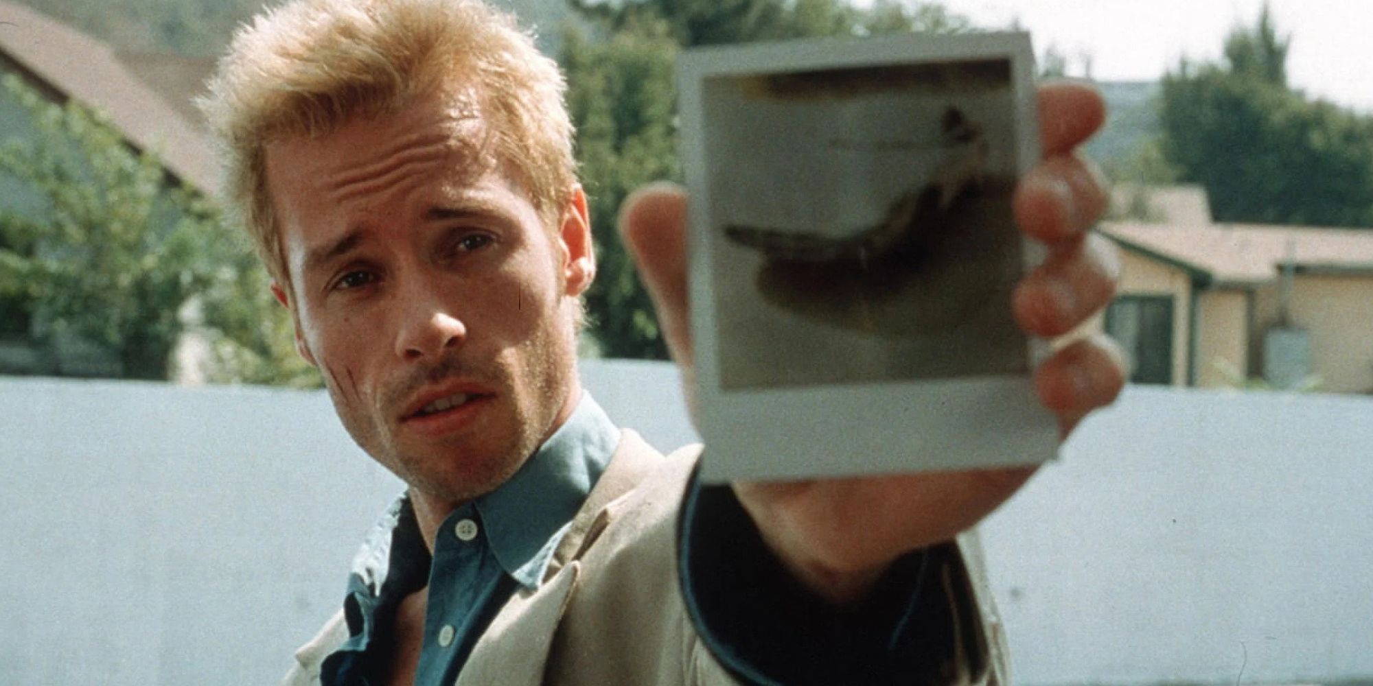 Guy Pearce holding out a polaroid photograph in 'Memento'