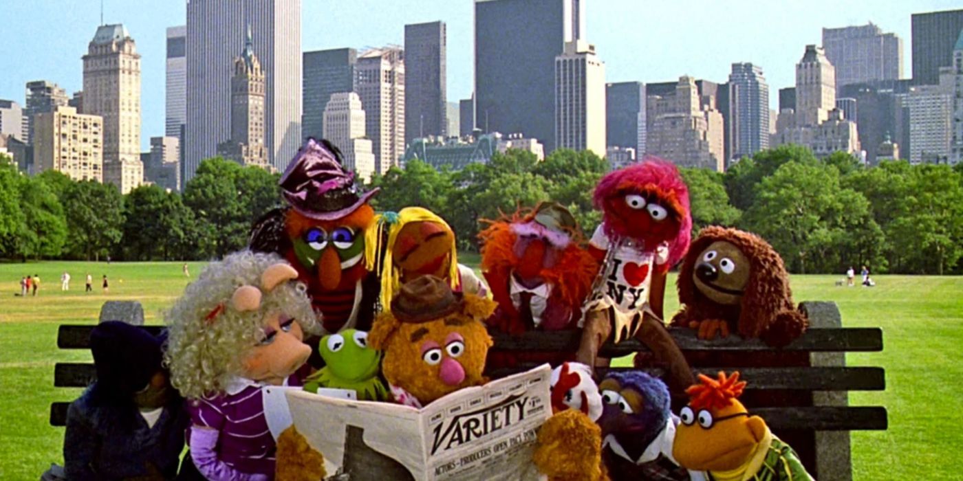 Kermit, Miss Piggy et d'autres Muppets se rassemblent autour de Fozzie, qui lit un journal Variety sur un banc devant les gratte-ciel de Manhattan dans 