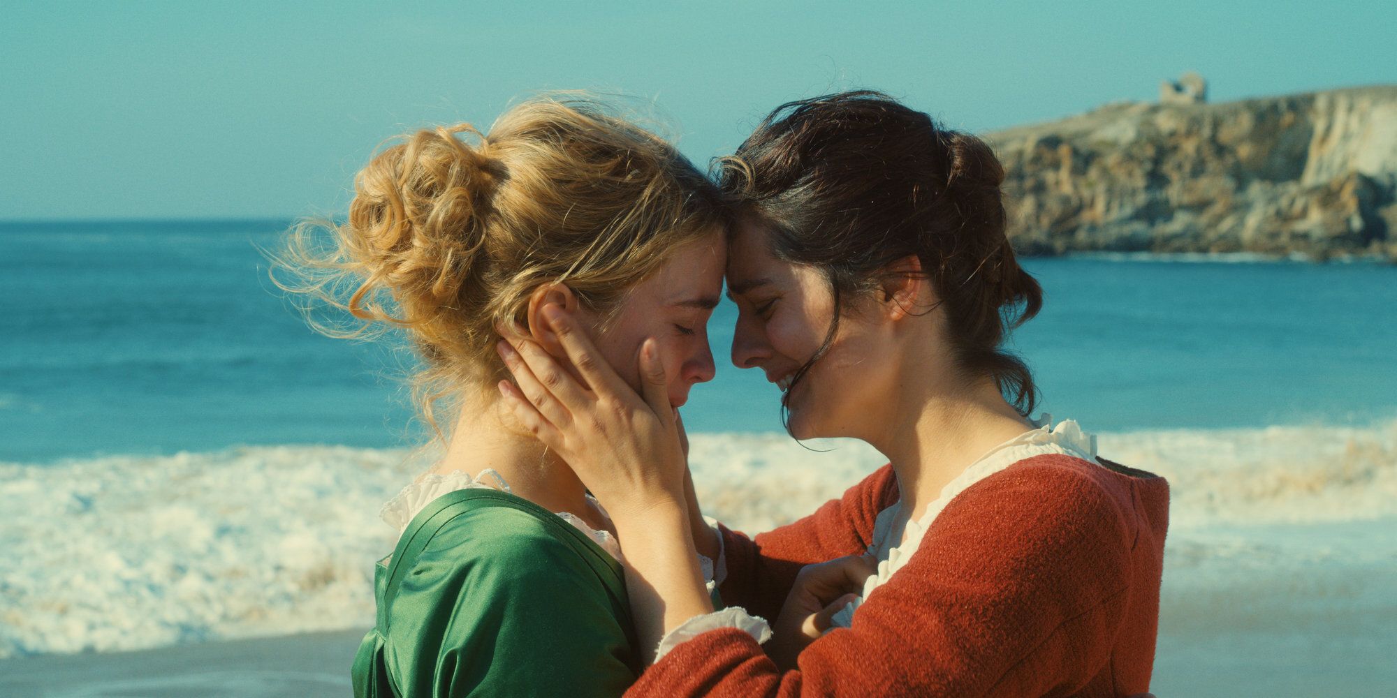 Noémie Merlant tenant le visage d'Adèle Haenel dans ses mains et se touchant les fronts dans 'Portrait d'une dame en feu'.