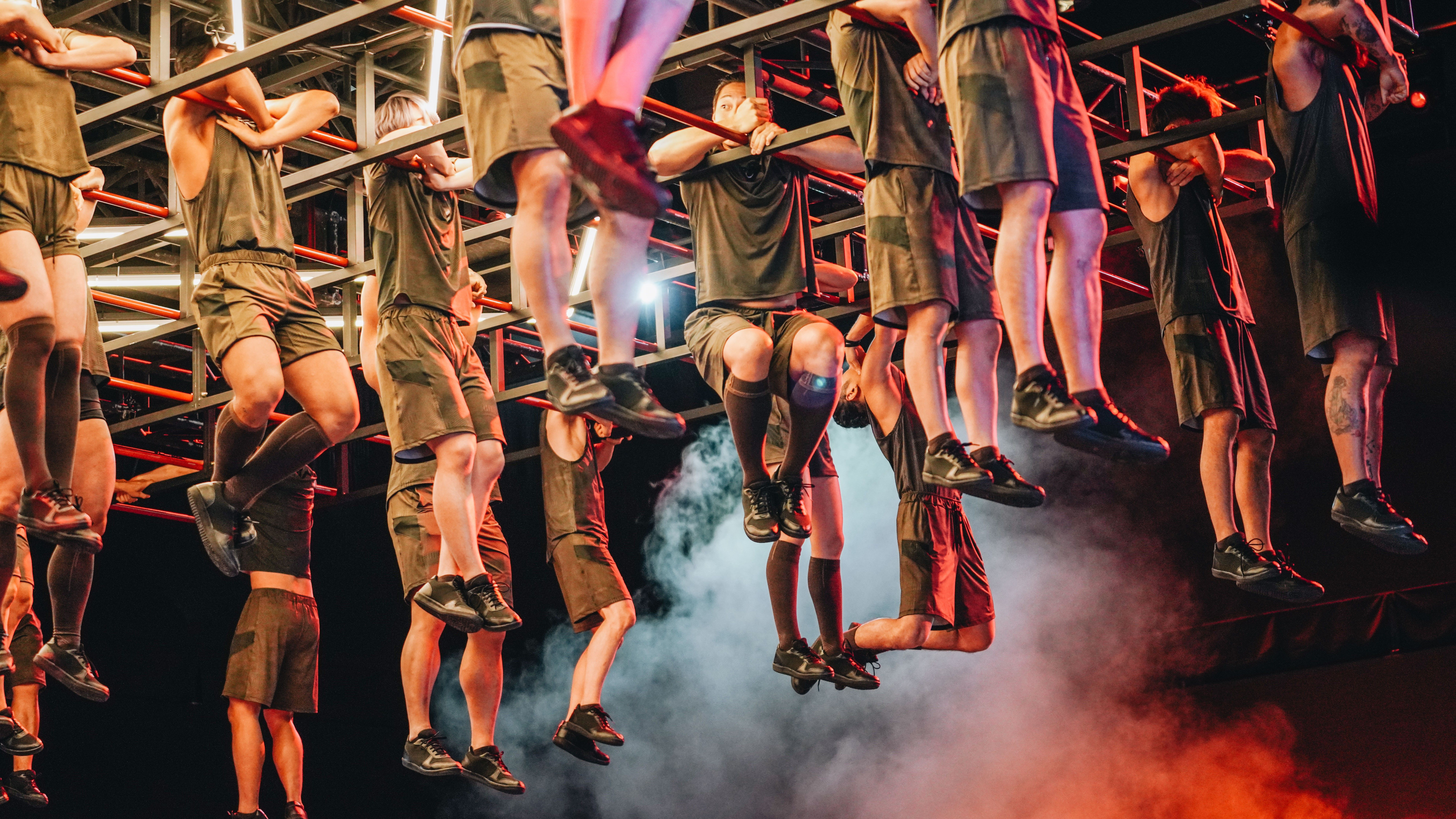 Contestants on Physical: 100 participate in the competition's first challenge, hanging from bars for as long as they can.