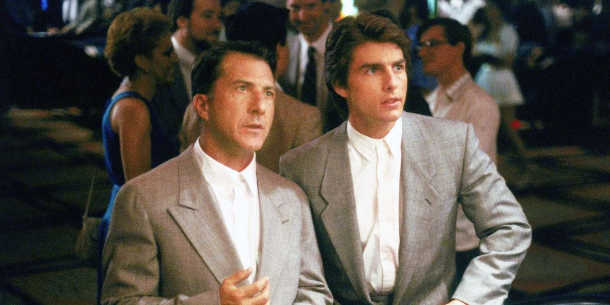 Raymond (Dustin Hoffman) and Charlie Babbit (Tom Cruise) wearing suits and looking concerned at a casino in Rain Man