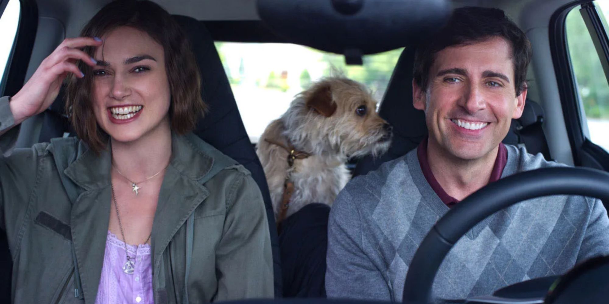 A young woman and man in car with dog laughing