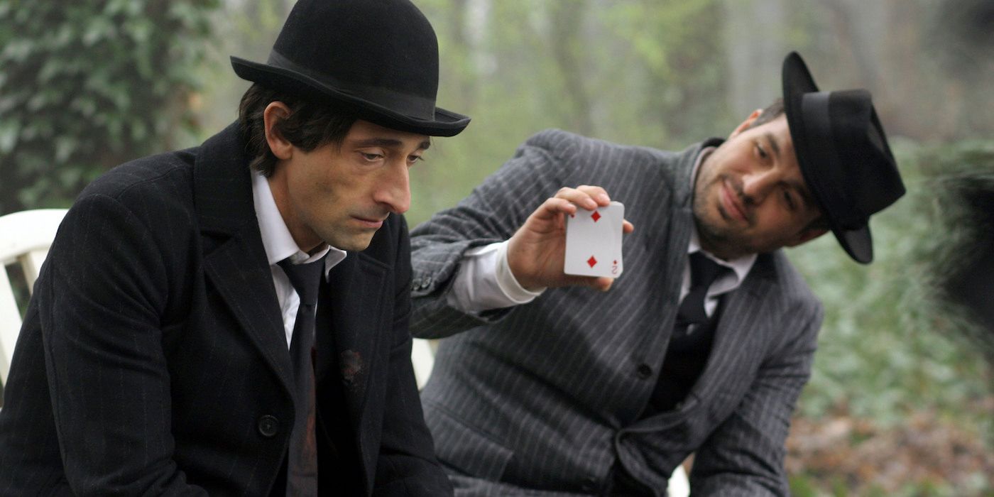 Mark Ruffalo montre une carte à jouer à Adrien Brody sur un banc public dans Les Frères Bloom.