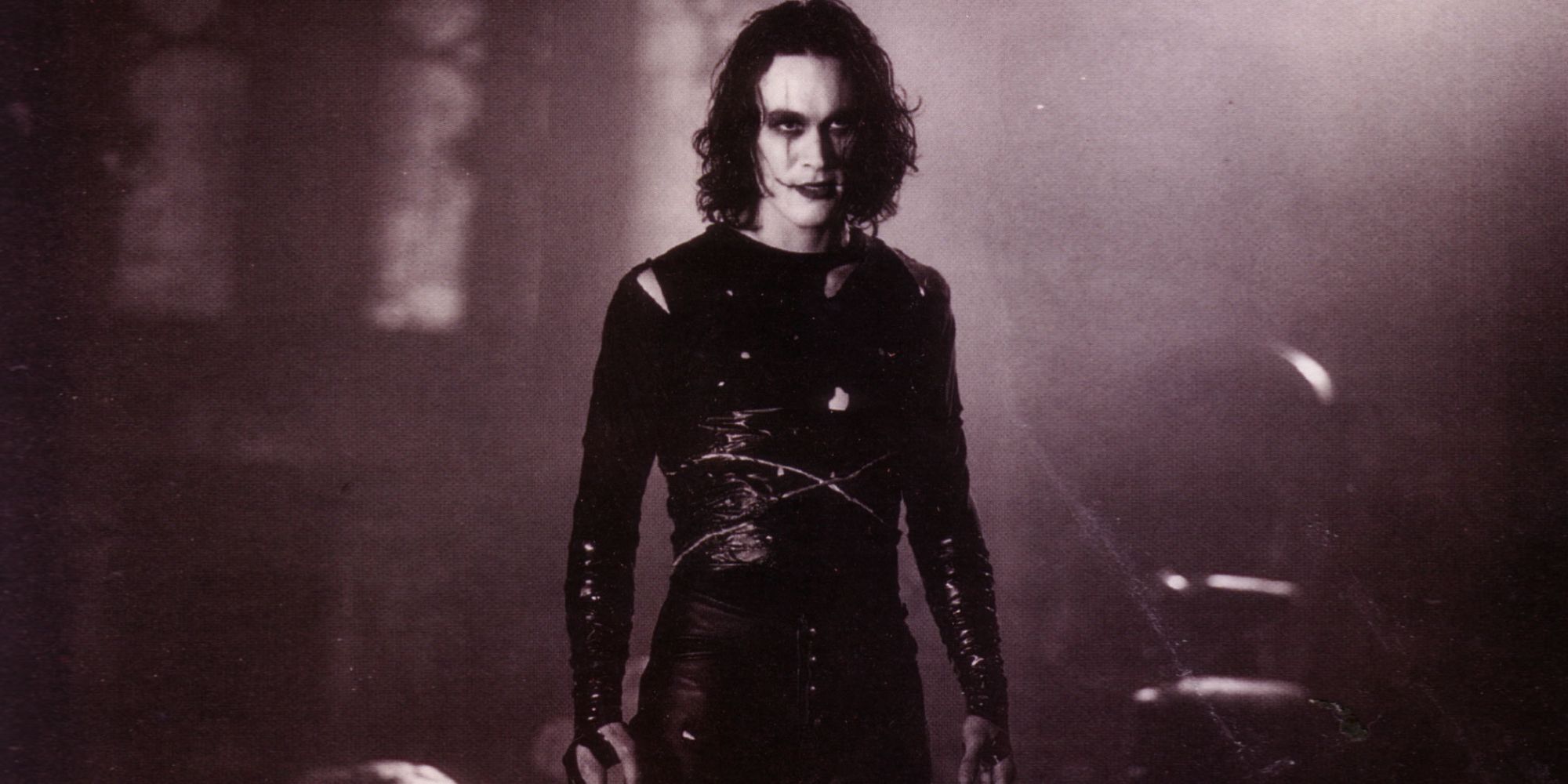 Brandon Lee as Eric Draven in the full black costume and white face makeup in The Crow